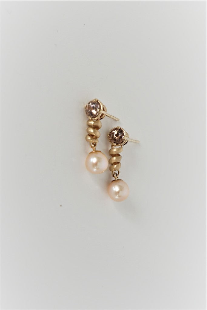 These earrings with "cognac" colored zircon gemstones flash brightly, as spirals of yellow gold dangle with cultured pearls from your ears for a look that gets you noticed! Below the two 5mm round "cognac" colored zircons (totaling .80carats), are spirals of 14K yellow gold with dangling natural "peach" colored, 5mm round pearls. These earrings have medium weight posts and friction backs for comfortable and secure wear.  3/4"L x 3/8"'w x 3/8"d